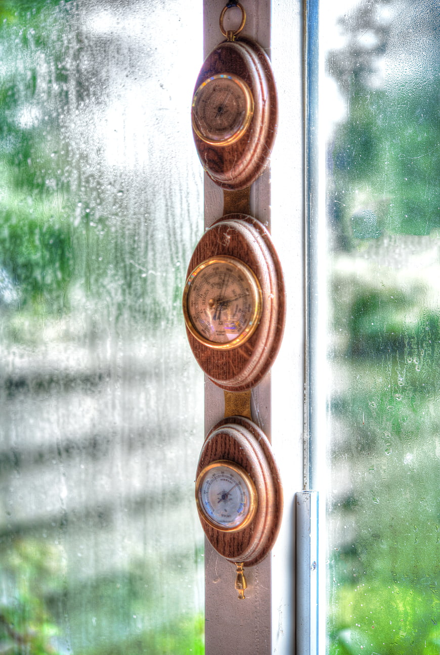 Vintage wooden barometer hanging on rainy window frame