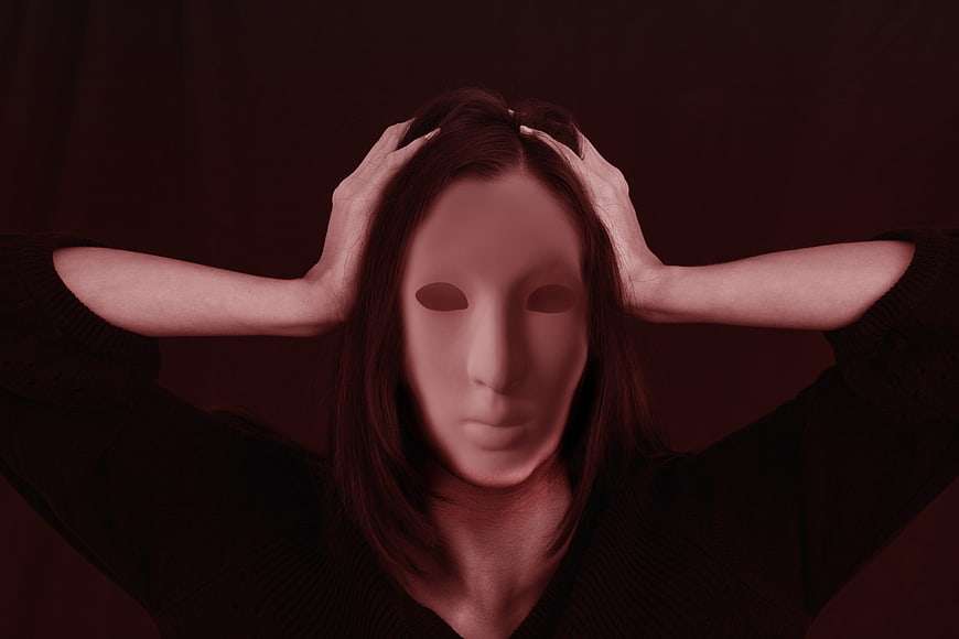 Woman Wearing White Mask Holding Head in Red Light