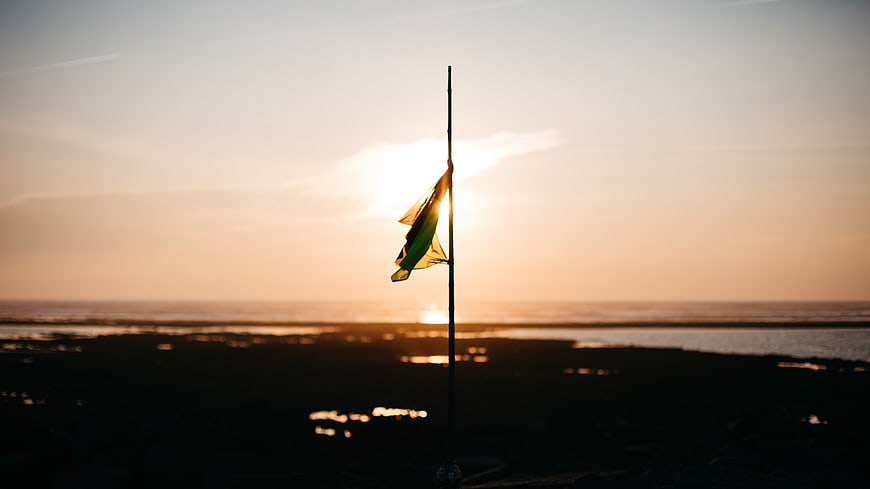 Silhouetted Flag on Beach at Sunset