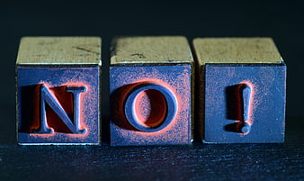 Wooden rubber stamps spelling NO with red ink on dark background