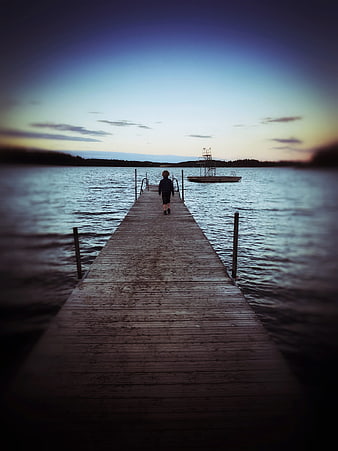 Child walking on wooden pier at dusk