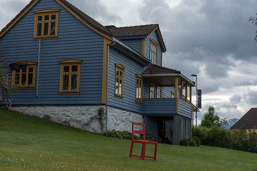 Blue wooden house with red chair on grassy hill