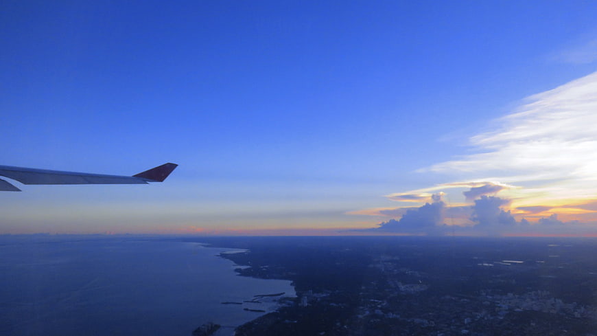 Airplane Wing View Over Coastline at Sunset