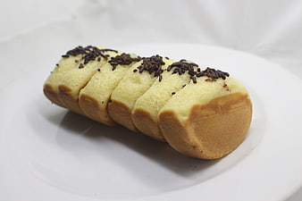 Golden Sponge Cake Roll with Sesame Seeds on White Plate