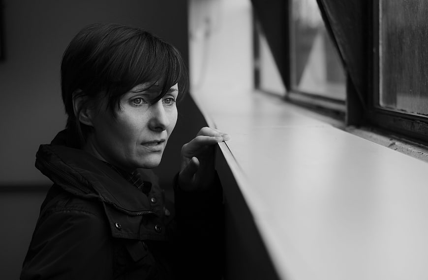 Pensive woman looking out window in black and white