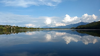 Serene Lake Weissensee Reflection with Mountains and Clouds