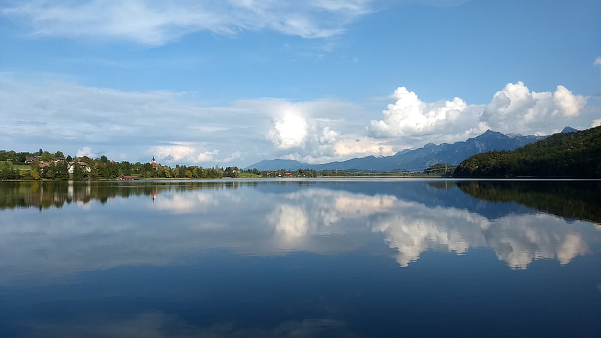 Serene Lake Weissensee Reflection with Mountains and Clouds