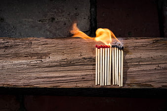 Burning matchsticks on rustic wooden plank background