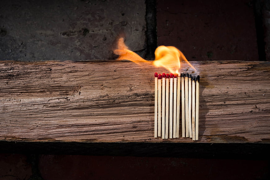 Burning matchsticks on rustic wooden plank background