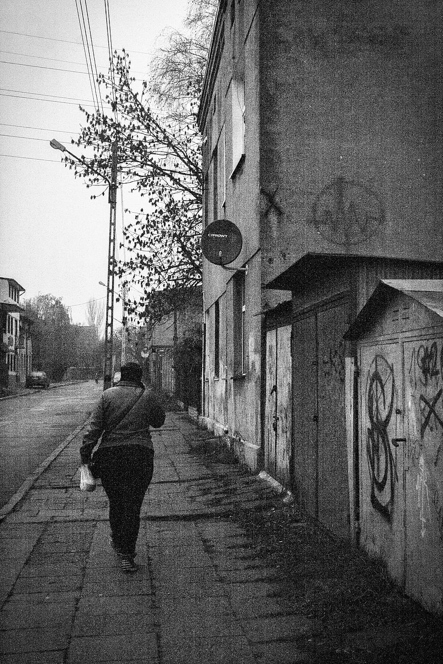 Black and white photo of person walking down urban street