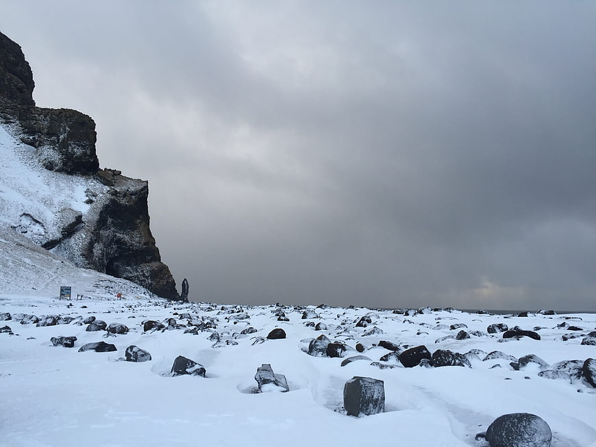 Snowy black rock beach in Iceland under overcast sky