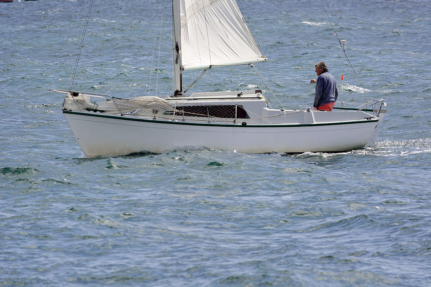 Man sailing white boat on blue sea