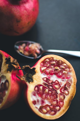 Fresh Pomegranate Cut in Half with Seeds on Spoon