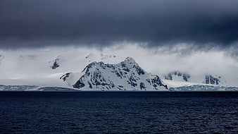Dramatic Snow-Capped Mountains Rising from Dark Ocean Waters