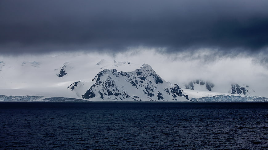 Dramatic Snow-Capped Mountains Rising from Dark Ocean Waters