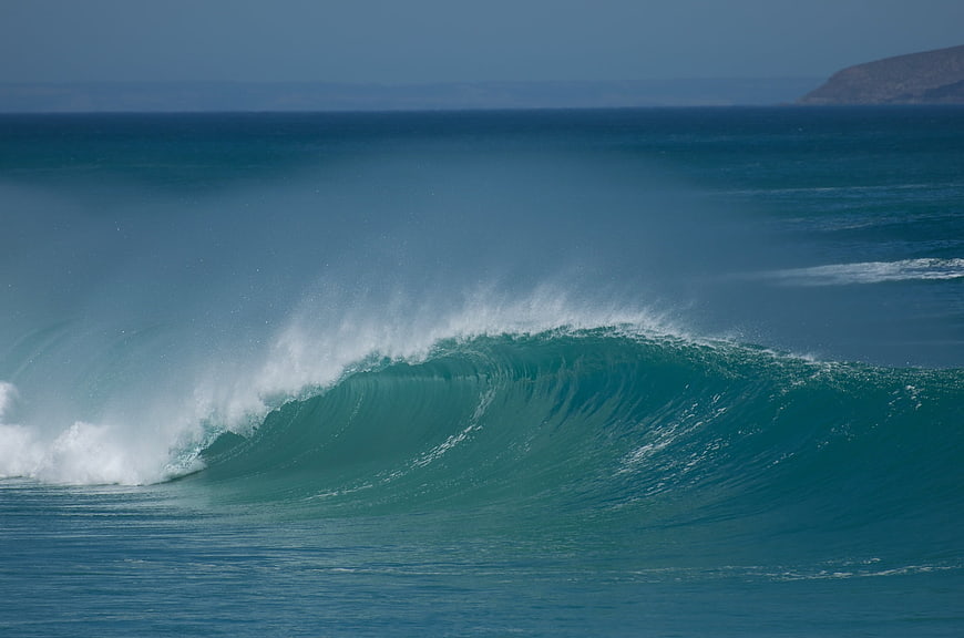 Powerful turquoise ocean wave crashing with white spray