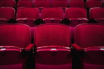 Rows of empty red cinema seats in a dark theater