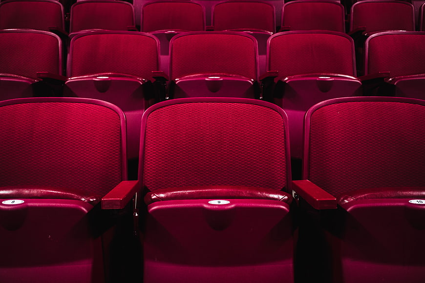 Rows of empty red cinema seats in a dark theater