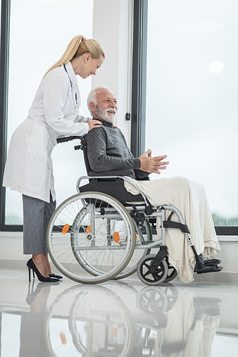 Female doctor comforting elderly male patient in wheelchair