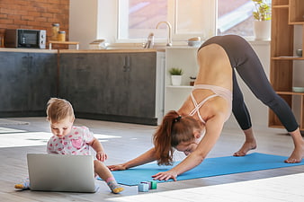 Mother doing yoga while toddler plays with laptop at home