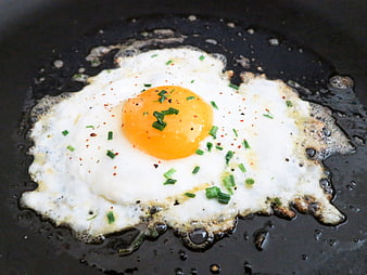 Fried Egg With Chives And Pepper In A Black Pan