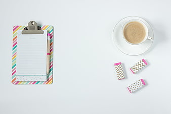 Flat lay of clipboard, coffee, and erasers on white desk