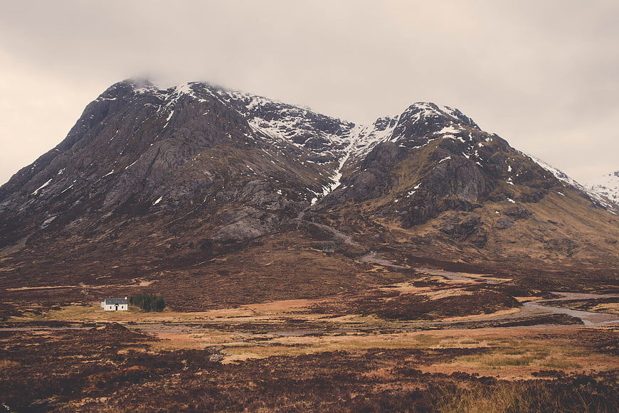 Solitary white cottage in rugged Scottish Highlands landscape