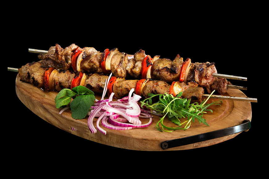 Grilled meat skewers with vegetables on wooden board