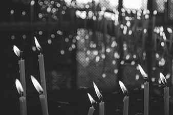 Black and white photo of lit candles with bokeh background