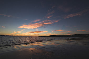 Serene Sunset Over Ocean Beach with Cloud Reflections