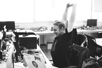 Happy Man Stretching Arms in Modern Office Workspace