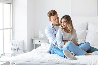 Happy couple hugging on bed in bright bedroom