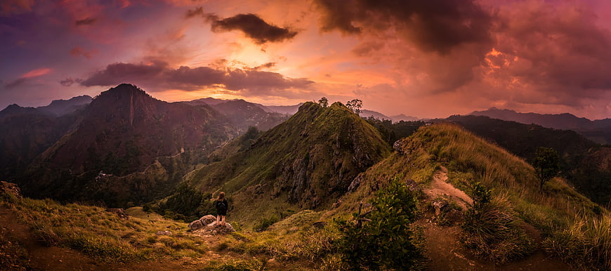 Hiker on Mountain Ridge at Dramatic Sunset Panorama