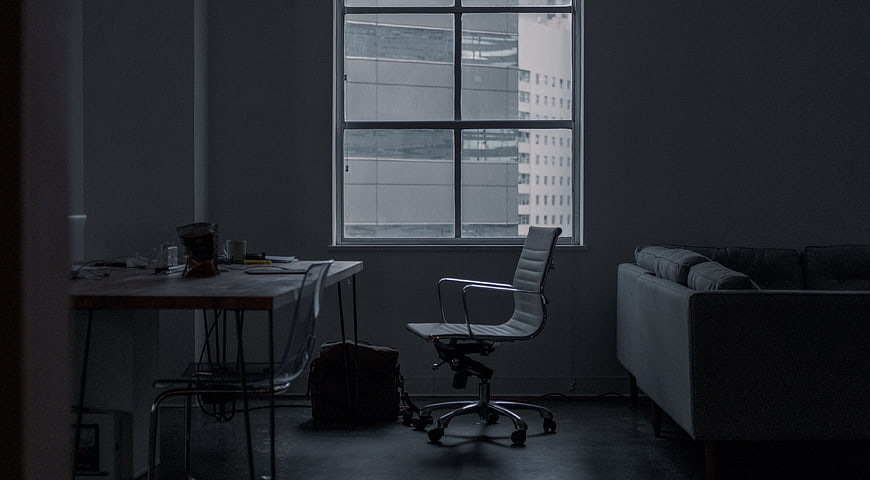 Dark moody office interior with desk and window