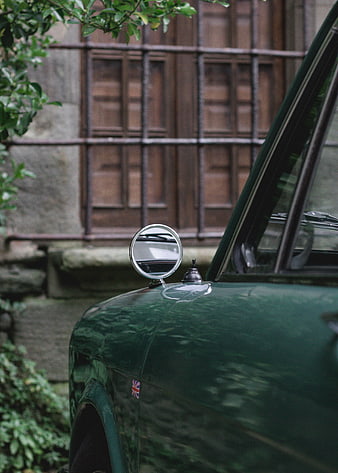 Close-up of vintage green car side mirror and hood