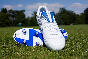 White and Blue Football Boots on Green Grass Field
