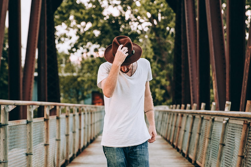 Man in Fedora Hat Walking on Bridge