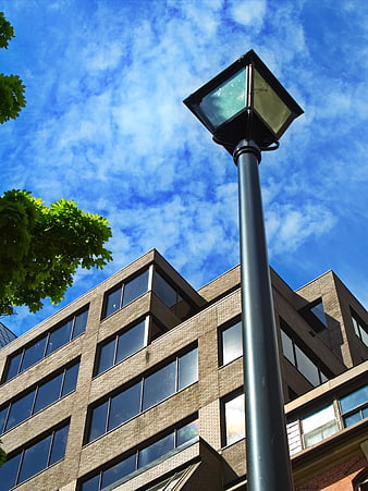 Low angle view of street lamp against blue sky and office building