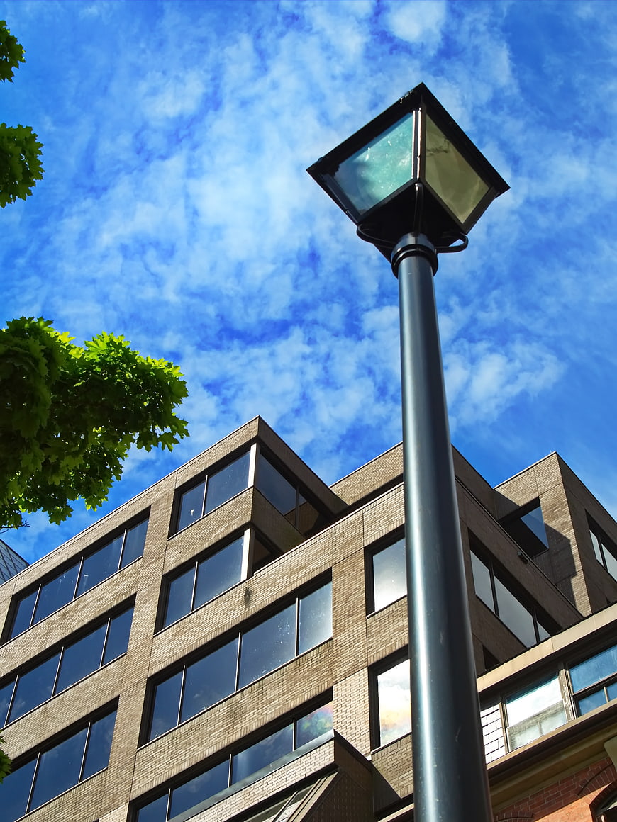 Low angle view of street lamp against blue sky and office building
