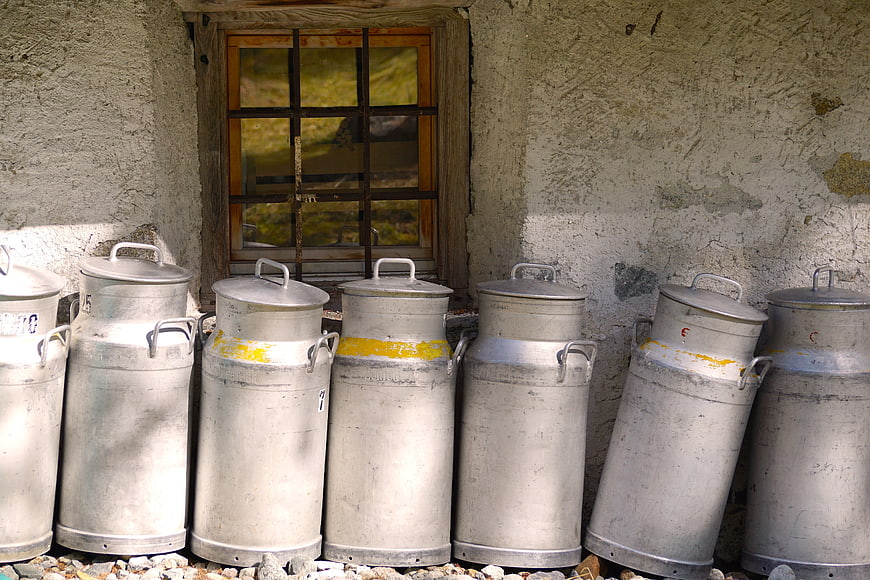 Vintage metal milk cans lined up against rustic wall