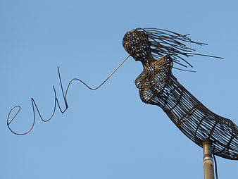 Metal wire mermaid sculpture against blue sky