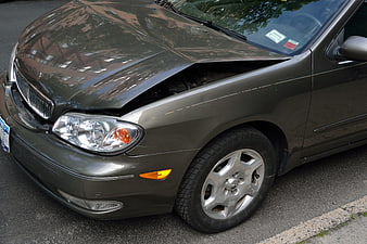 Damaged gray sedan with dented hood and open engine bay