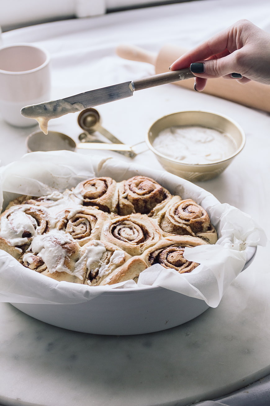 Hand Icing Freshly Baked Vegan Cinnamon Rolls