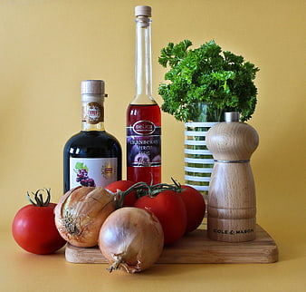 Still life of tomatoes, onions, vinegar, and parsley on a wooden board