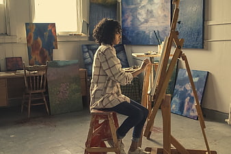 Woman artist painting in a creative studio with easel