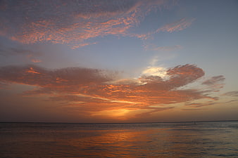 Vibrant Orange Sunset Over Calm Ocean with Textured Clouds