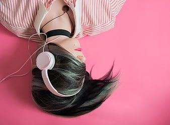 Woman with headphones lying on pink background