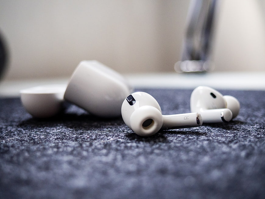 White Wireless Earbuds on Textured Dark Surface