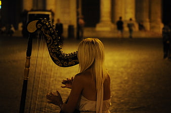 Blonde Woman Playing Harp at Night in City Square