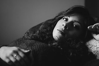 Black and white portrait of a woman lying down with curly hair